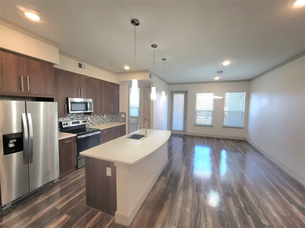 a large kitchen with sink a refrigerator and wooden floor