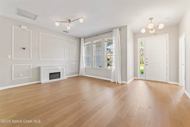 a view of a livingroom with a fireplace a ceiling fan and windows