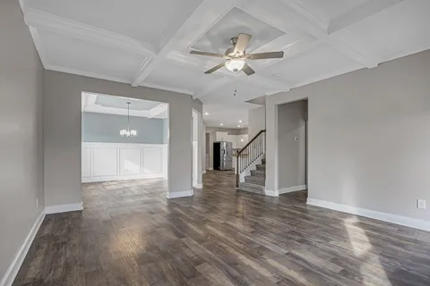 a view of an empty room with wooden floor and a ceiling fan