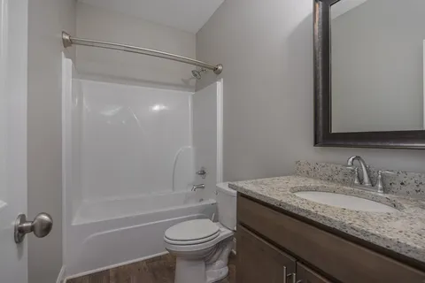 a bathroom with a granite countertop sink toilet and shower