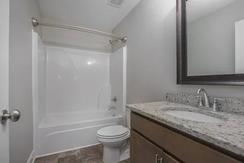 a bathroom with a granite countertop sink toilet and shower