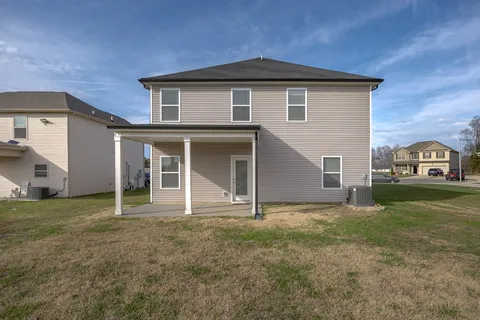a white house that has a small yard and trees in front of it