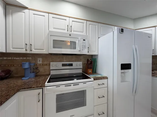 a kitchen with white cabinets and white appliances