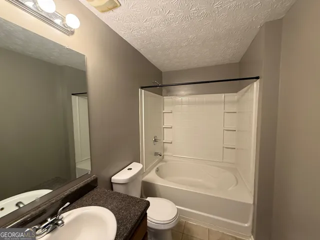 a bathroom with a granite countertop bathtub toilet and sink