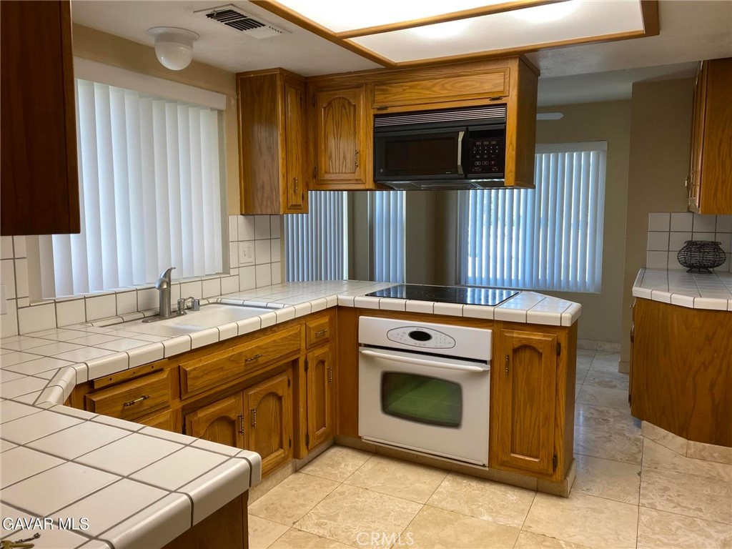 22601 Player Court Tehachapi, CA 93561 - Photo 4 of 10 a kitchen with stainless steel appliances wooden cabinets sink and stove
