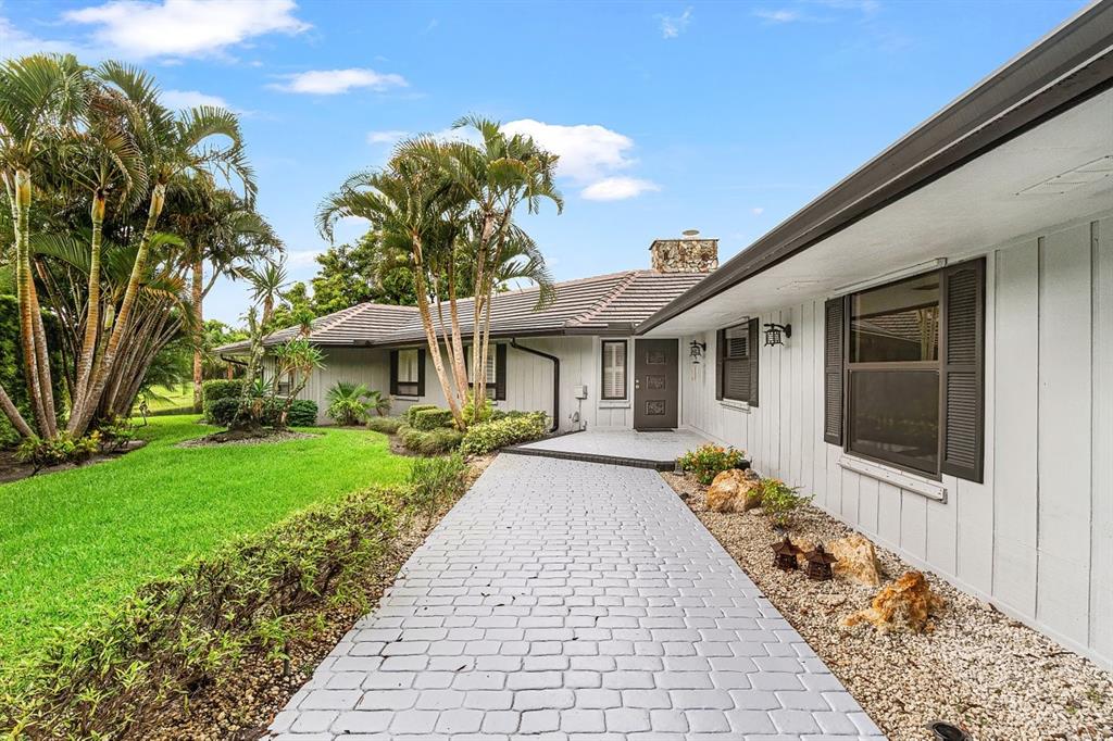 10158 Southeast Acorn Way Jupiter, FL 33469 - Photo 2 of 39 a front view of a house with a garden and plants