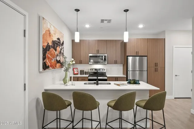 a kitchen with stainless steel appliances kitchen island granite countertop a refrigerator a stove a sink and chairs with wooden floor