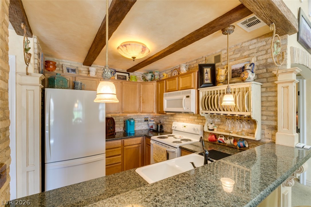 9325 West Desert Inn Road, Unit 244 Las Vegas, NV 89117 - Photo 22 of 55 A warm kitchen features granite counters, ceiling beams, and integrated appliances.
