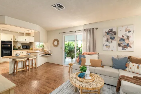 a living room with furniture large window and kitchen view
