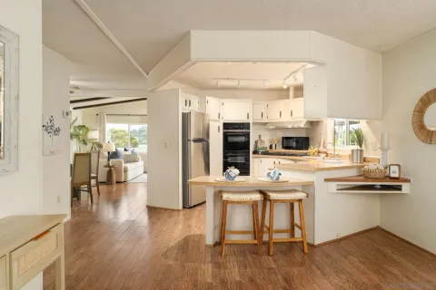 a kitchen with stainless steel appliances a dining table chairs and wooden floor