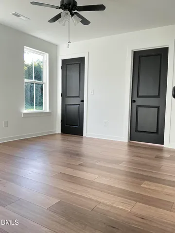 an empty room with wooden floor cabinet and windows