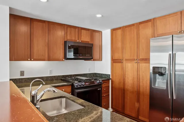 a kitchen with stainless steel appliances granite countertop a refrigerator stove and sink