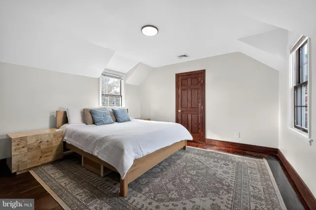 a bedroom with a large bed and wooden floor