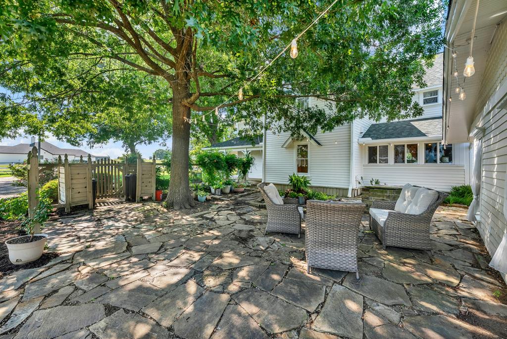 1425 Lone Star Road Celina, TX 75009 - Photo 22 of 40 A charming flagstone courtyard creates a peaceful outdoor retreat beneath the shade of mature oak trees. String lighting, lush landscaping, and ample seating provide the perfect setting for morning coffee, quiet evenings, or entertaining guests.