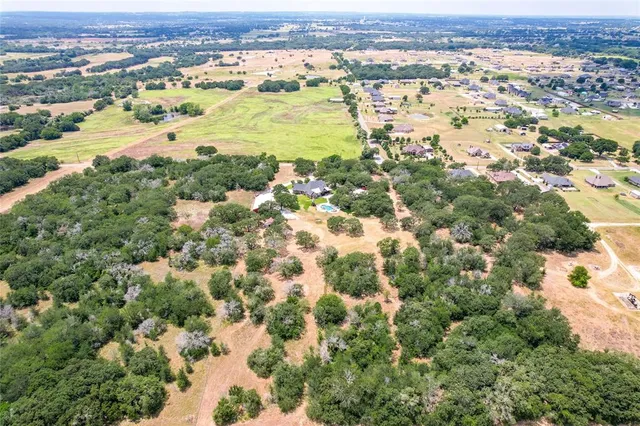 an aerial view of residential houses with outdoor space and trees