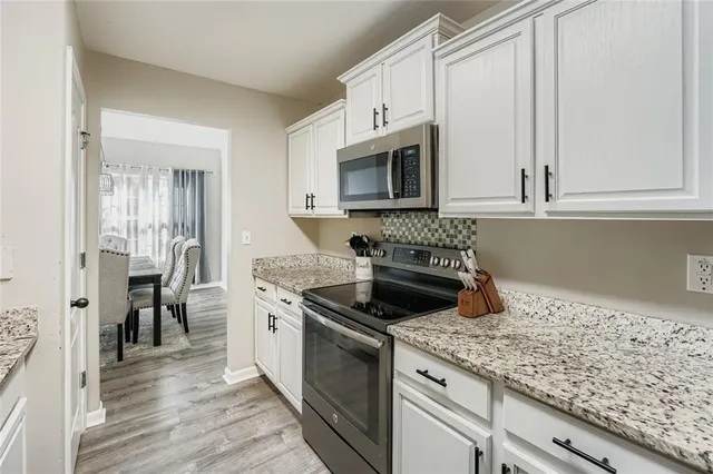 a kitchen with granite countertop white cabinets and stainless steel appliances
