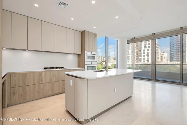 a kitchen with kitchen island granite countertop a stove top oven sink and cabinets