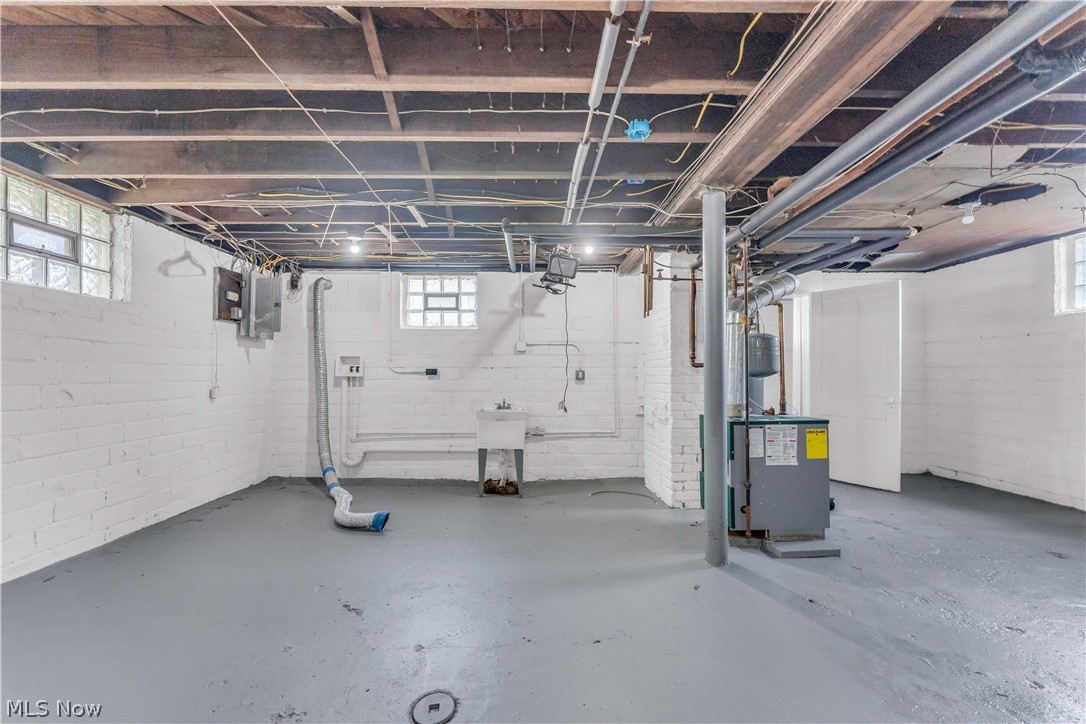 3506 Riverside Avenue Cleveland, OH 44109 - Photo 26 of 31 Spacious unfinished basement featuring painted concrete walls, painted concrete flooring, exposed ceiling joists, and glass block windows