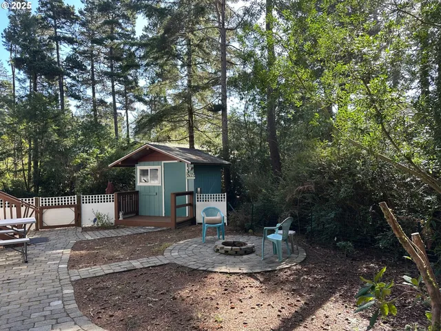 a view of a wooden house with a yard and large trees