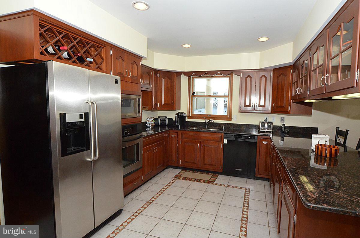 7900 Bennett Branch Road Mount Airy, MD 21771 - Photo 3 of 30 a kitchen with stainless steel appliances granite countertop a refrigerator a sink dishwasher a stove with wooden cabinets and floor