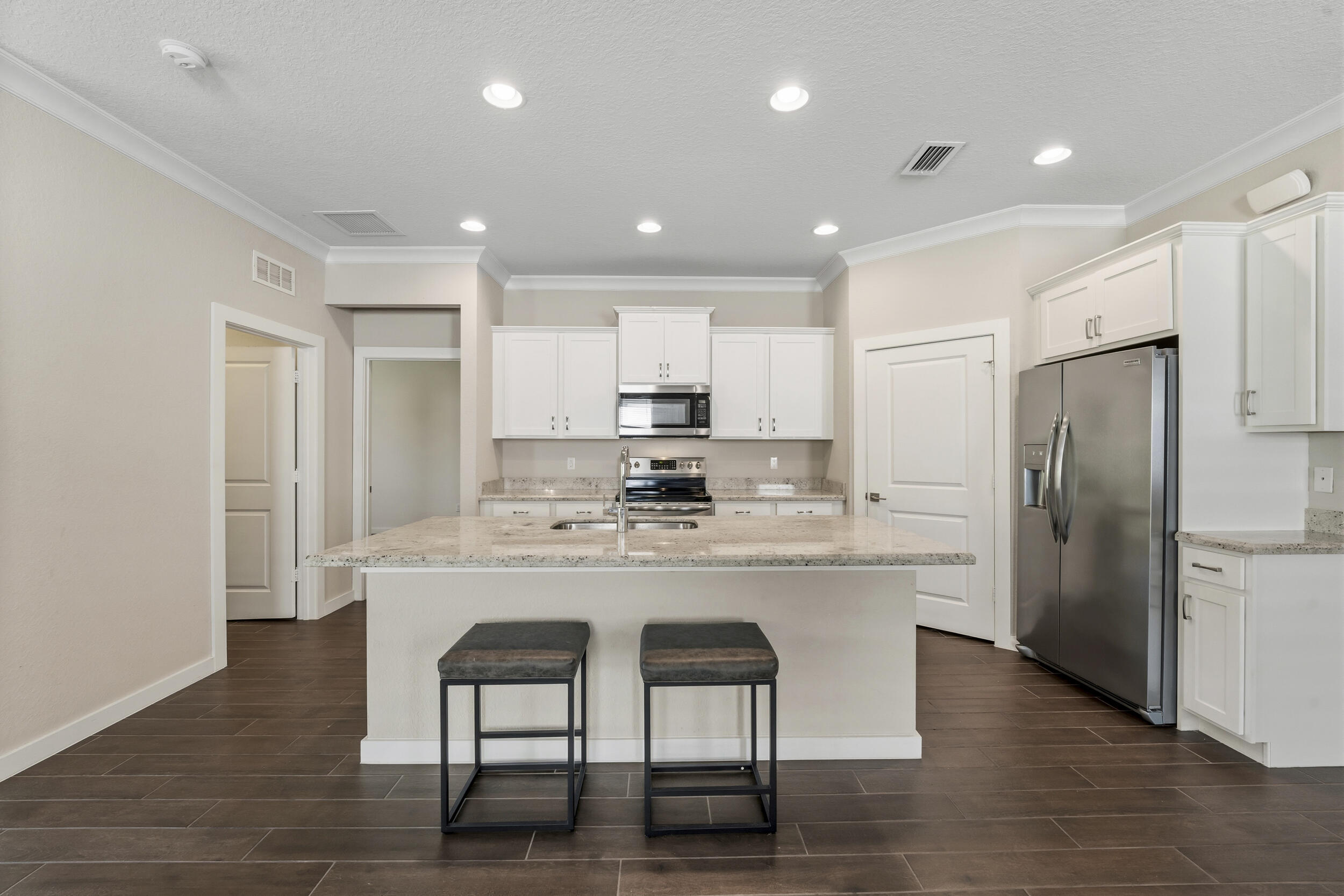 7461 Southwest Harbor Cove Drive Stuart, FL 34997 - Photo 11 of 30 a kitchen with stainless steel appliances granite countertop a dining table chairs refrigerator and cabinets