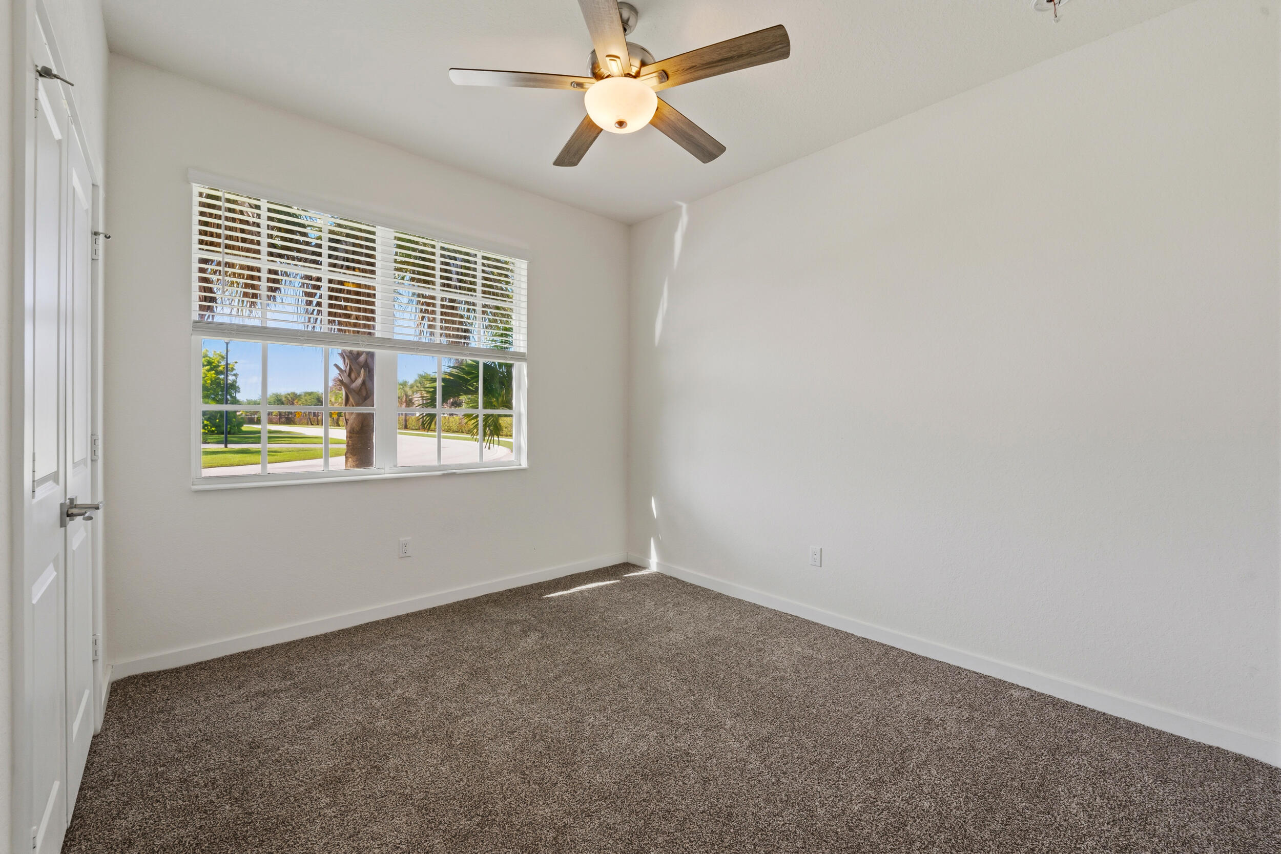 7461 Southwest Harbor Cove Drive Stuart, FL 34997 - Photo 14 of 30 an empty room with chandelier fan and windows
