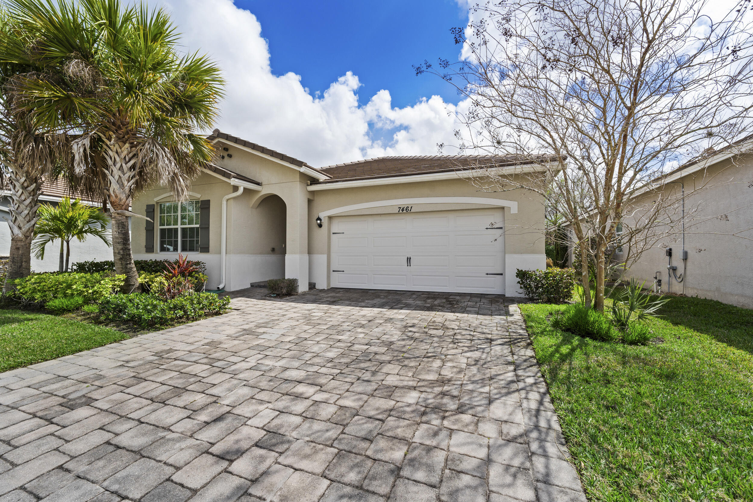7461 Southwest Harbor Cove Drive Stuart, FL 34997 - Photo 2 of 30 a front view of house with yard and trees around
