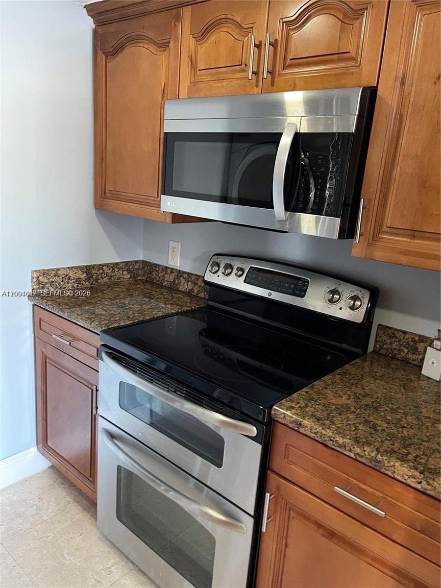 2415 Northwest 16th St Road, Unit 102 Miami, FL 33125 - Photo 11 of 19 a kitchen with granite countertop a stove and a microwave