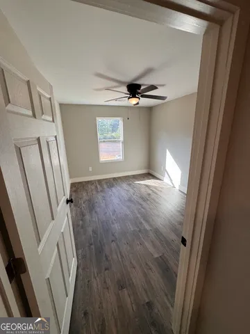 a view of empty room with wooden floor and fan