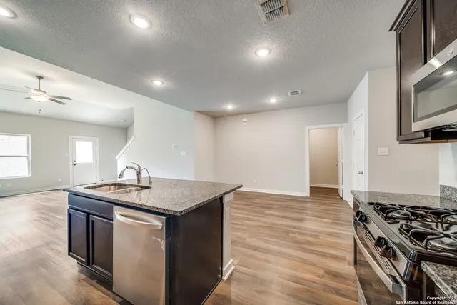 a view of kitchen with microwave stove refrigerator and cabinets