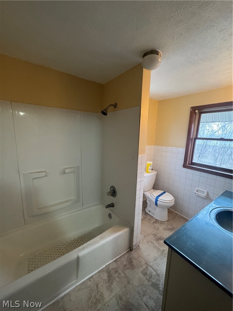 577 Rhodes Avenue Akron, OH 44307 - Photo 11 of 19 Bathroom with vanity, tub / shower combination, wainscoting, tile walls, and a textured ceiling