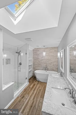 a bathroom with a granite countertop sink a toilet a large mirror and shower