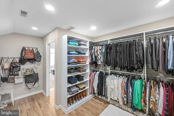 a view of walk in closet with clothes and shoes