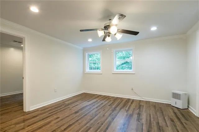 an empty room with wooden floor chandelier fan and windows