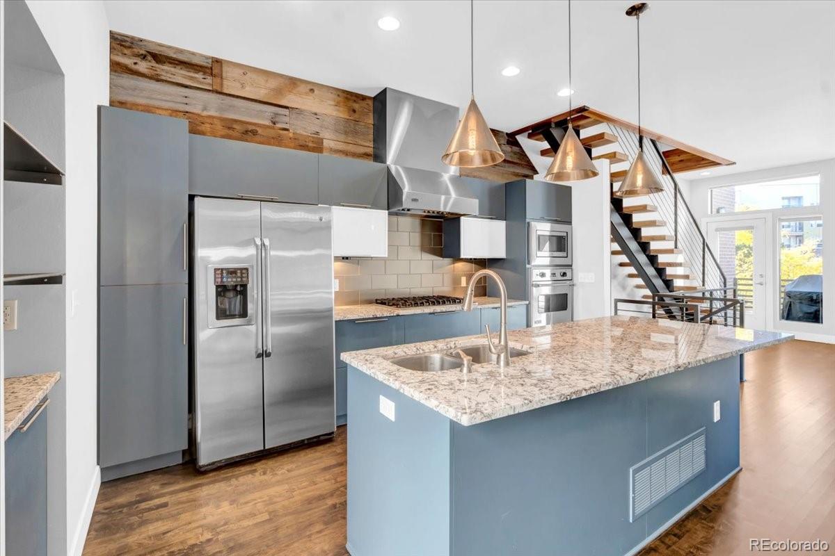 2900 Inca Street, Unit 15 Denver, CO 80202 - Photo 15 of 40 a kitchen with stainless steel appliances granite countertop a sink a refrigerator and a wooden floor