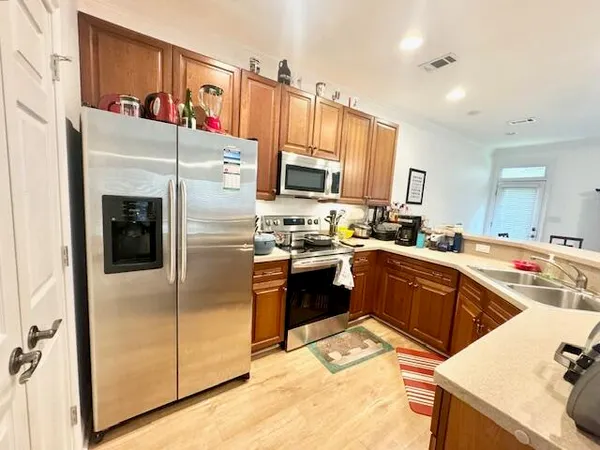 a kitchen with stainless steel appliances kitchen island granite countertop a refrigerator a sink a stove and oven