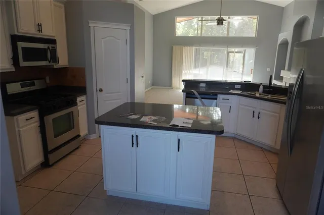 a kitchen with granite countertop a stove sink and microwave