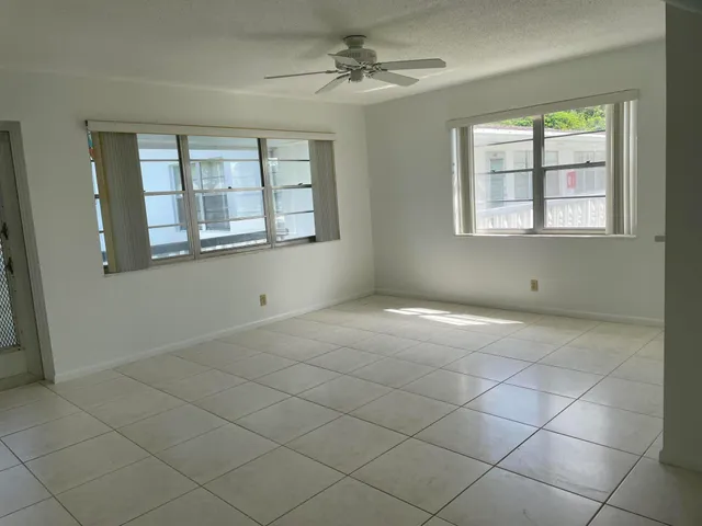 an empty room with windows and fan