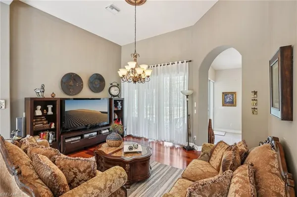 a living room with furniture a flat screen tv and a chandelier