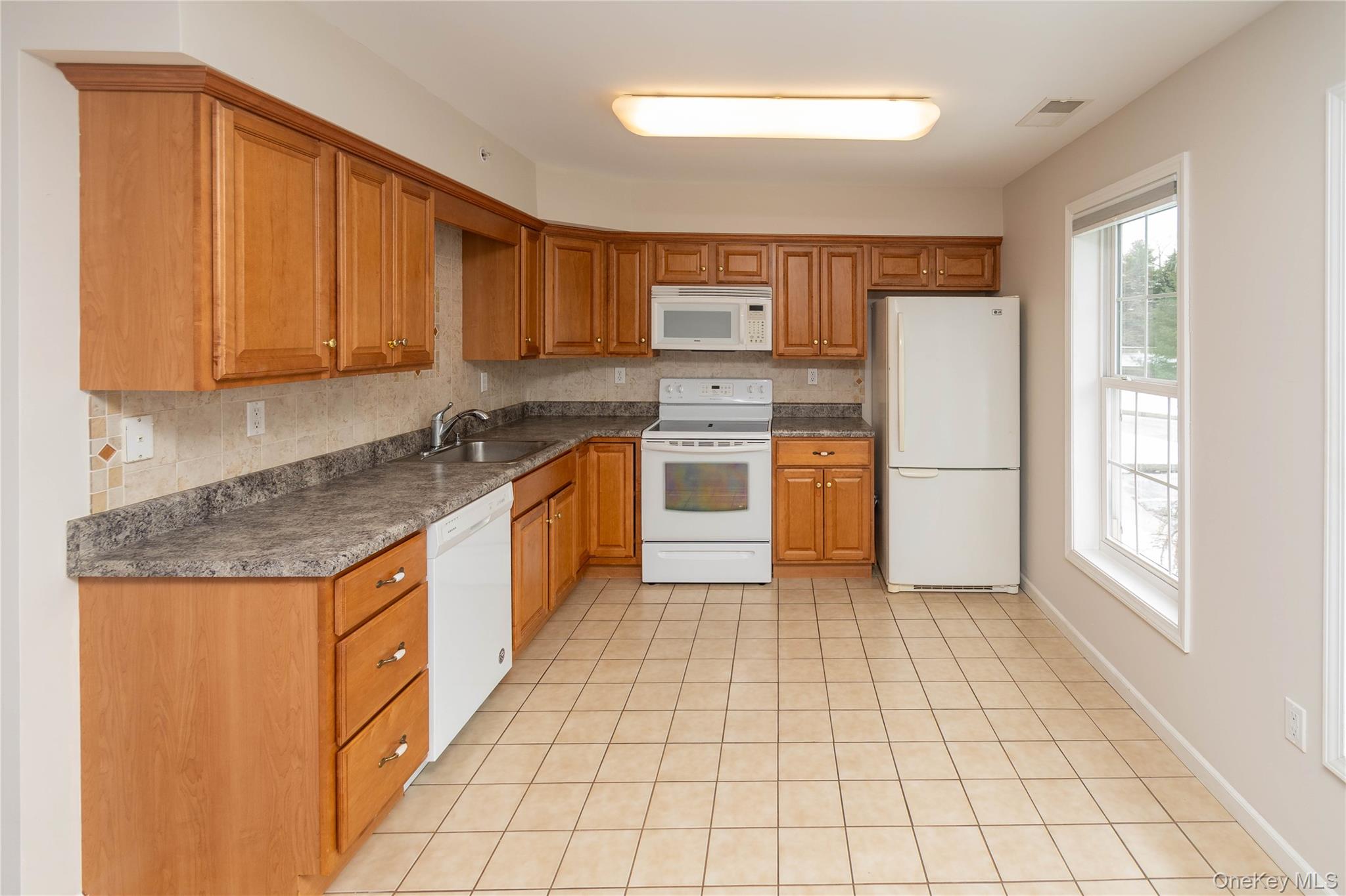 70 Aveonis Court Fishkill, NY 12524 - Photo 4 of 19 Kitchen with white appliances, dark countertops, brown cabinets, and decorative backsplash