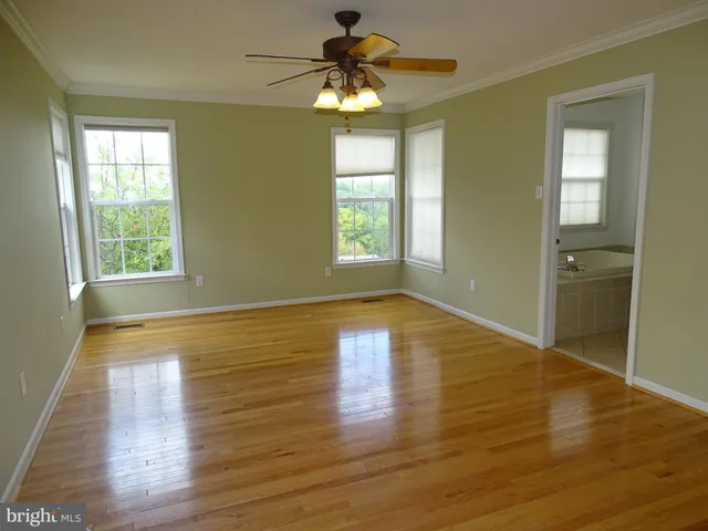 a view of empty room with wooden floor and fan