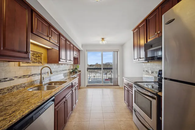 a kitchen with stainless steel appliances granite countertop a sink stove and cabinets