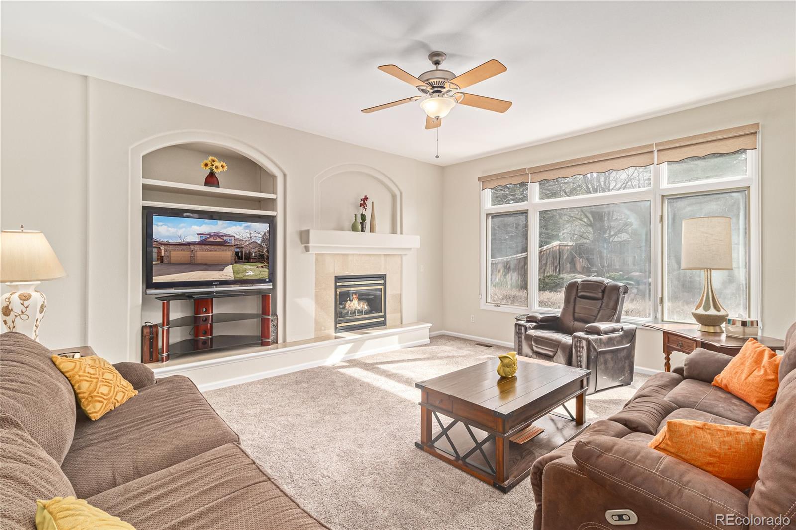 10152 Knoll Circle Highlands Ranch, CO 80130 - Photo 11 of 34 a living room with furniture a ceiling fan a fireplace and a large window