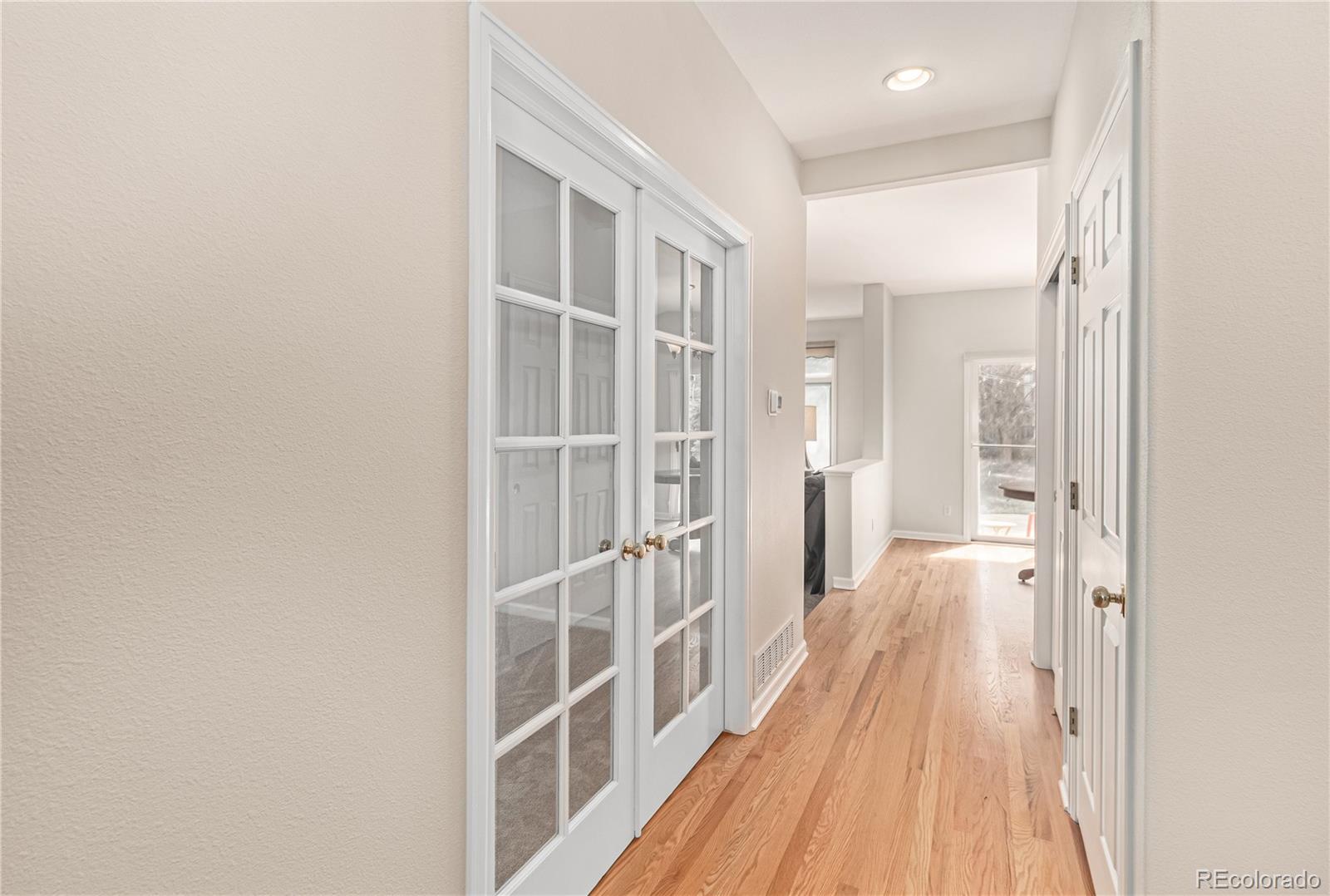 10152 Knoll Circle Highlands Ranch, CO 80130 - Photo 7 of 34 a view of a hallway with wooden floor and a bathroom