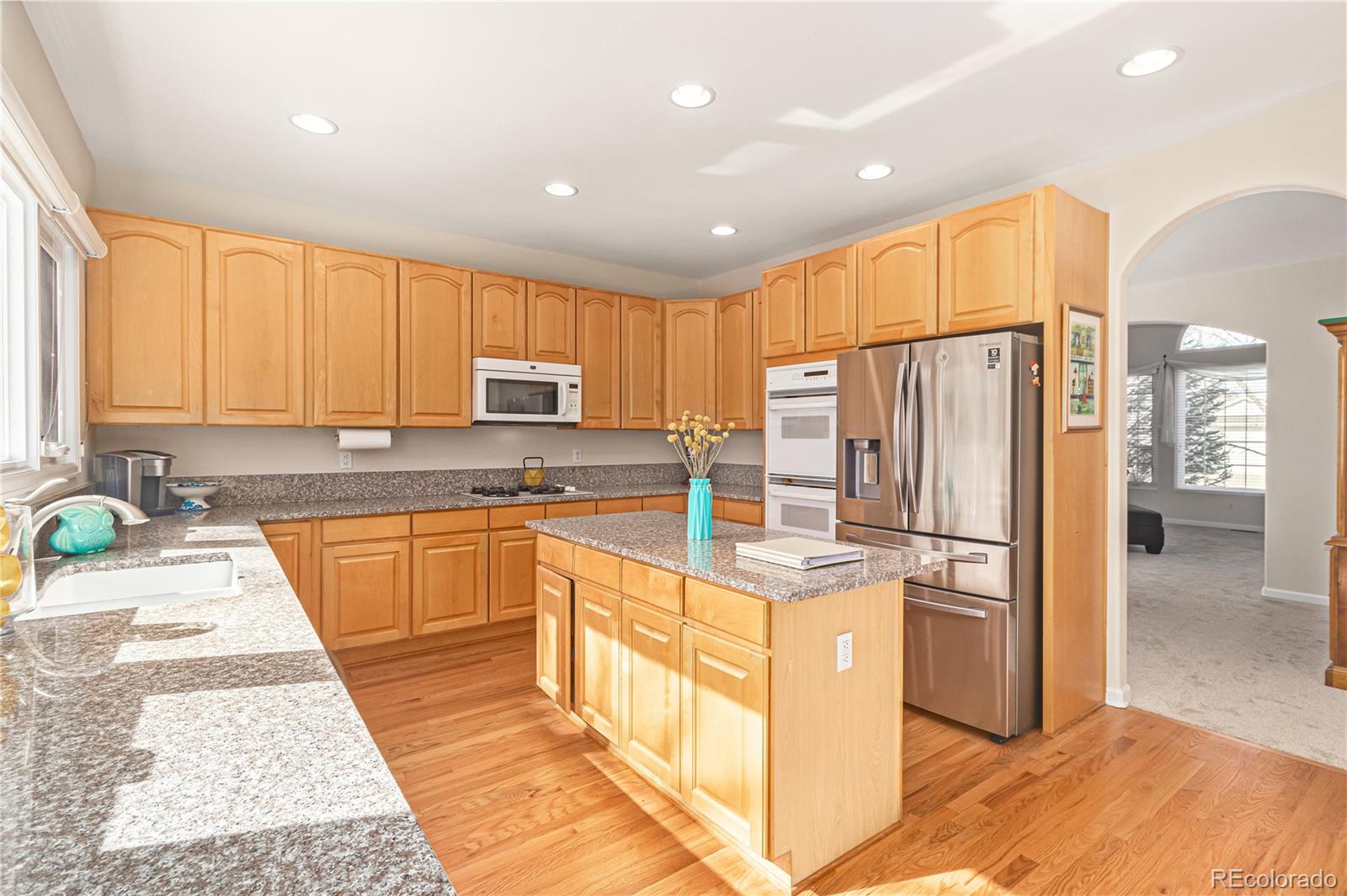 10152 Knoll Circle Highlands Ranch, CO 80130 - Photo 8 of 34 a kitchen with stainless steel appliances granite countertop a refrigerator a stove top oven and a sink with wooden floor