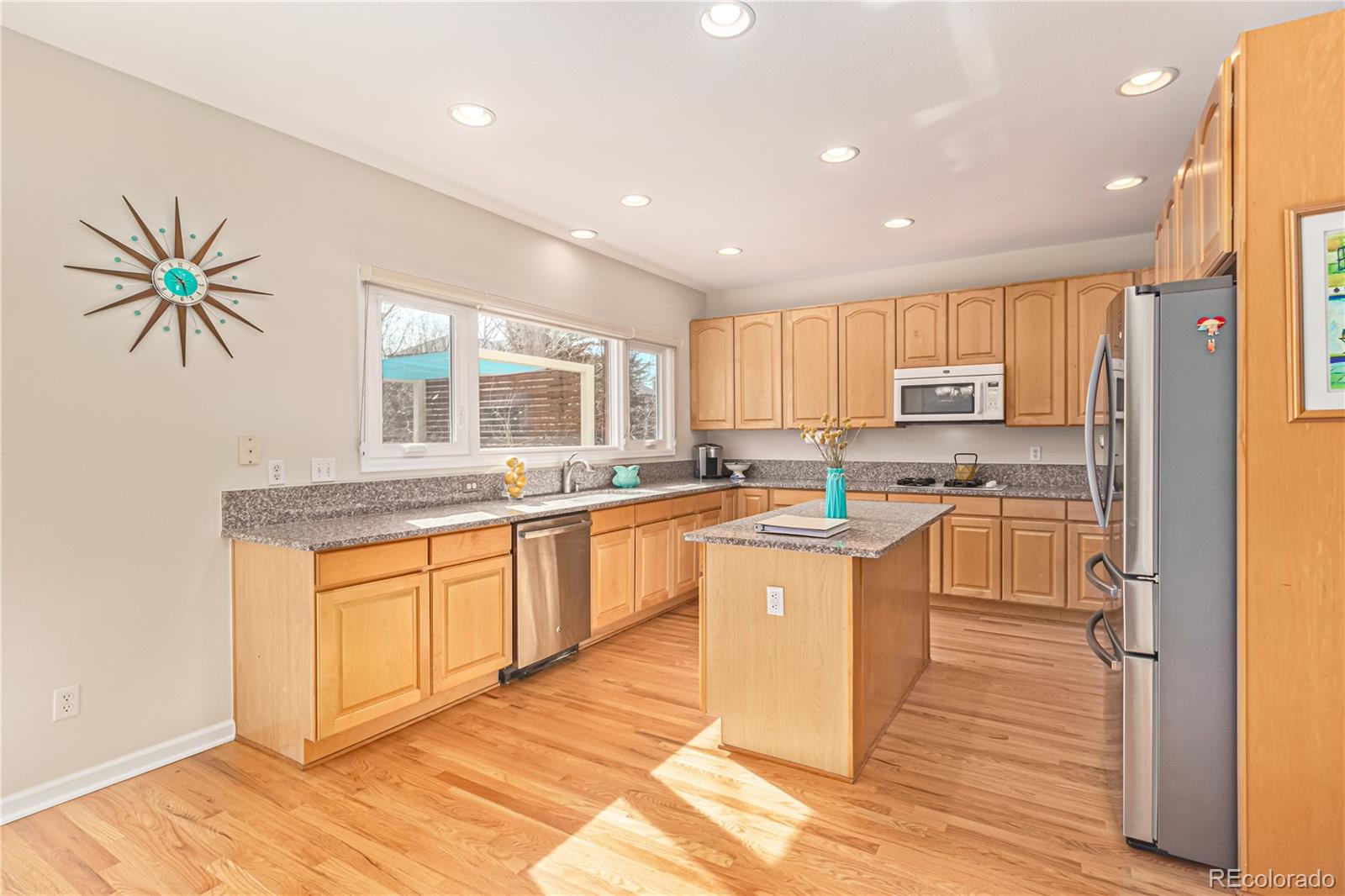 10152 Knoll Circle Highlands Ranch, CO 80130 - Photo 9 of 34 a kitchen with stainless steel appliances granite countertop a stove a sink dishwasher a refrigerator and white cabinets with wooden floor