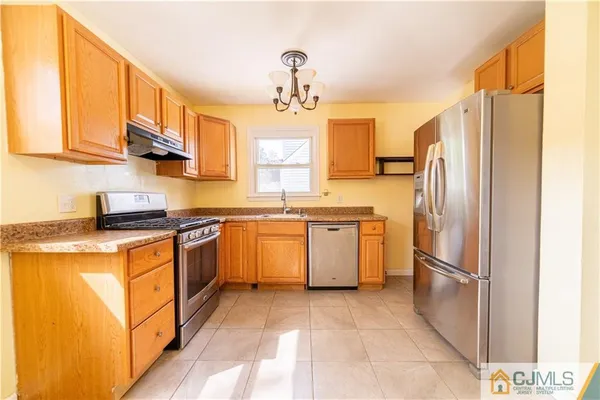 a kitchen with stainless steel appliances granite countertop a refrigerator a sink dishwasher a dining table and chairs with wooden floor