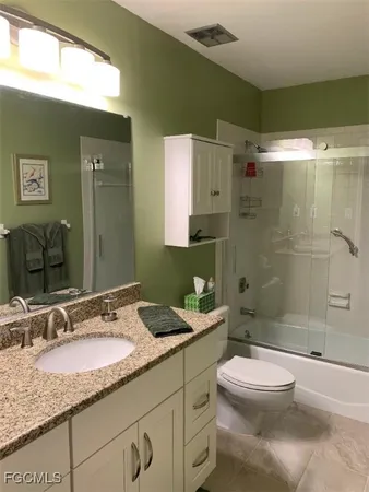 a bathroom with a granite countertop sink toilet mirror and shower