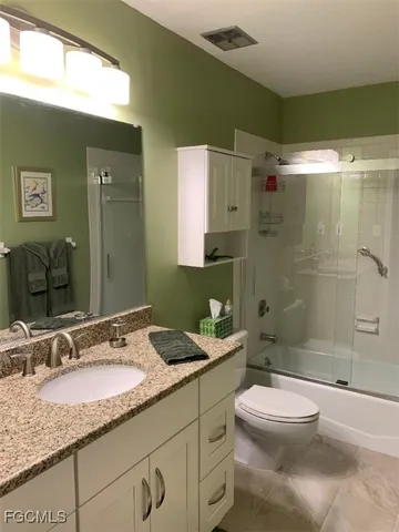 a bathroom with a granite countertop sink toilet mirror and shower