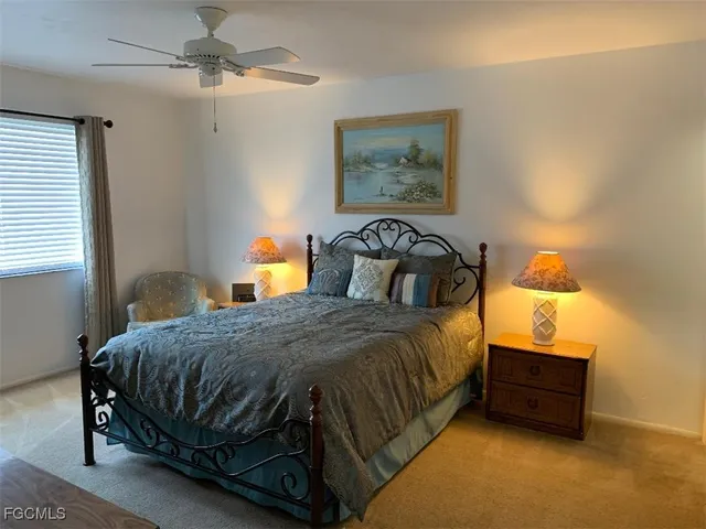 a bedroom with a bed a lamp on the dresser and a window